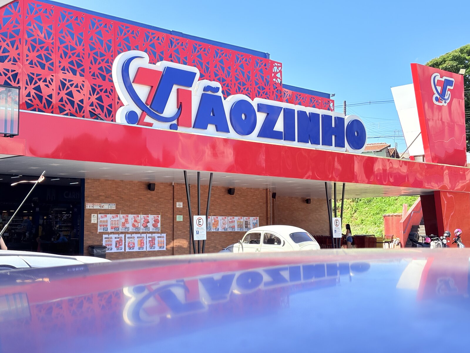 Supermercado Tiãozinho - Fachada em ACM vermelho com letreiro luminoso e revestimento decorativo